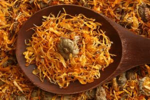 Wooden bowl with calendula seeds, illustrating summer natural health and beauty ideas to try at home