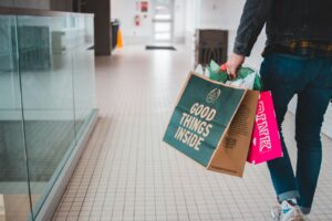 Image of someone carrying a paper shopping bag that says "Good things inside", to illustrate our article about making sustainable choices as a consumer.